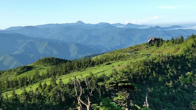 山頂付近から見る駒の小屋。後ろのプリンのような山は日光白根山です(2021.08.01　会津駒の小屋)