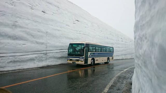 雪の大谷を走るバス