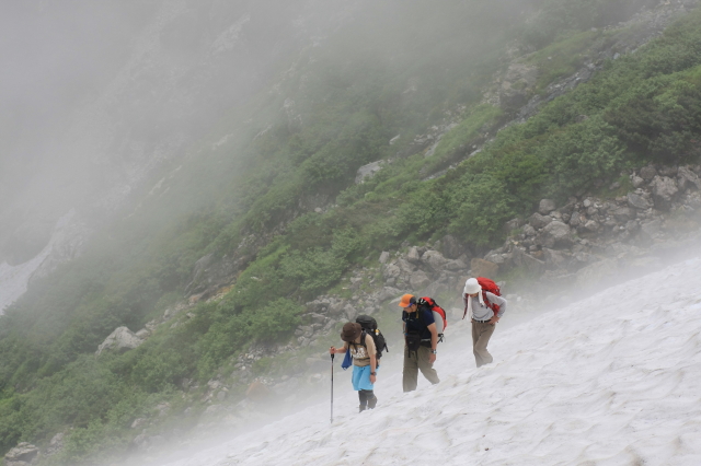 小雪渓のトラバースルートを歩く登山者 