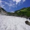 夏空のもと、大雪渓を登る登山者　