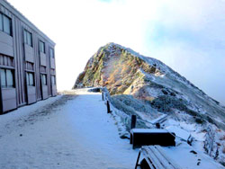 唐松岳頂上山荘と牛首です。山荘の前庭もうっすらと雪に覆われています。ガスの切れ間からは青空が見えてきました。