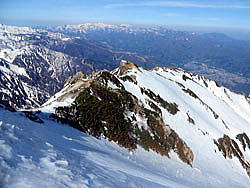 稜線より八方尾根最上部の下山口。八方尾根への下山口は、雪斜面のトラバースとなります。雪面状況に合わせて、慎重に通過しましょう。