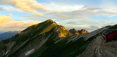 唐松岳と唐松岳頂上山荘です。朝日に照らされた唐松岳と不帰3峰です。　