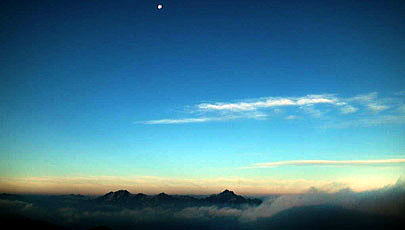 唐松岳頂上山荘前庭より　雲海に浮かぶ立山連峰・劔岳と上空の月。信州側　唐松沢の谷筋から唐松岳へと這い登ったガスが黒部側へフワリフワリと流れてきます。