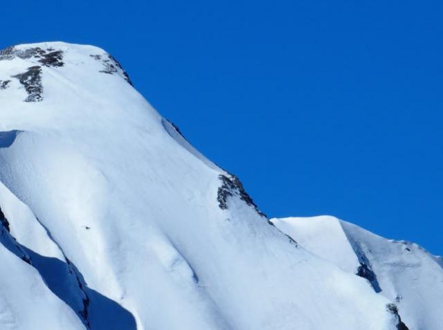 頂上までもう少し、鹿島槍ダイレクト尾根の核心部を越え、残された最後の雪稜を登る登山者が２人、尾根の右下に点になって見える