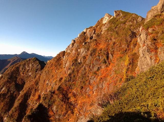 朝日に照らされる赤石沢の奥壁と、左手には摩利支天。奥には北岳と間ノ岳。