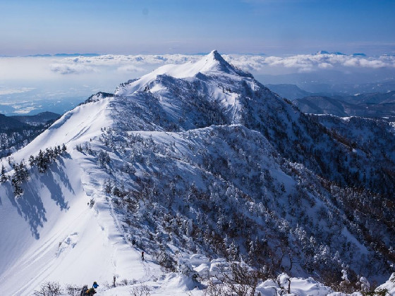 スカイブルーに雪の鋭峰と雲海の絶景